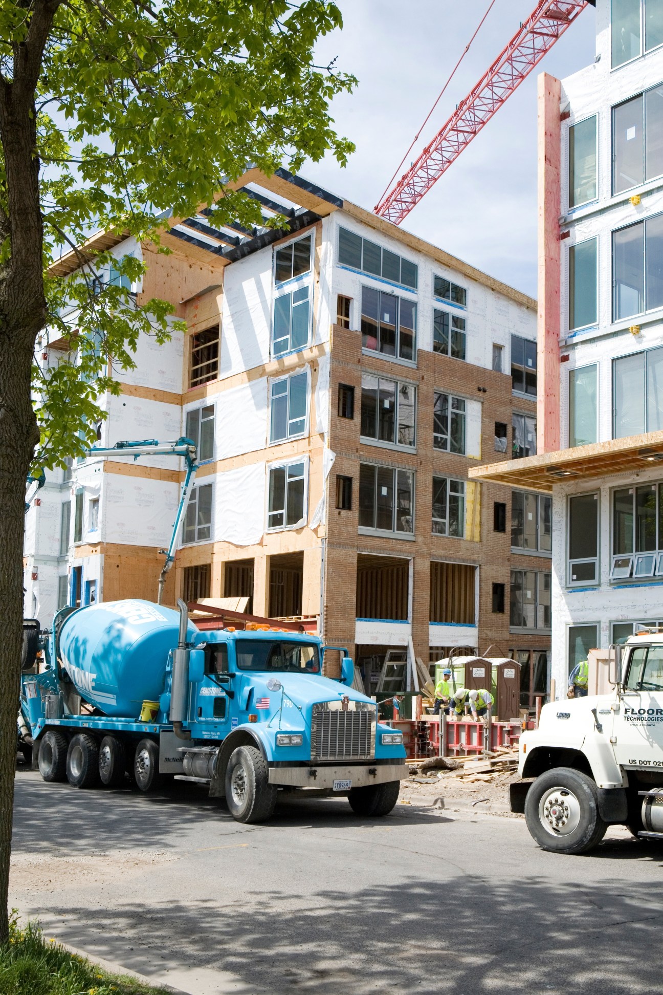Construction site of Blue apartments eco-friendly residences with mixed-material facade and building equipment.