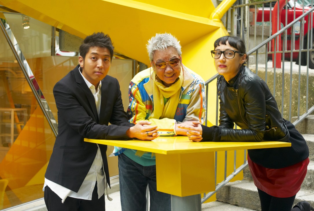 Three people pose at a bright yellow counter inside the 33will shop in Hong Kong's Sheung Wan district.