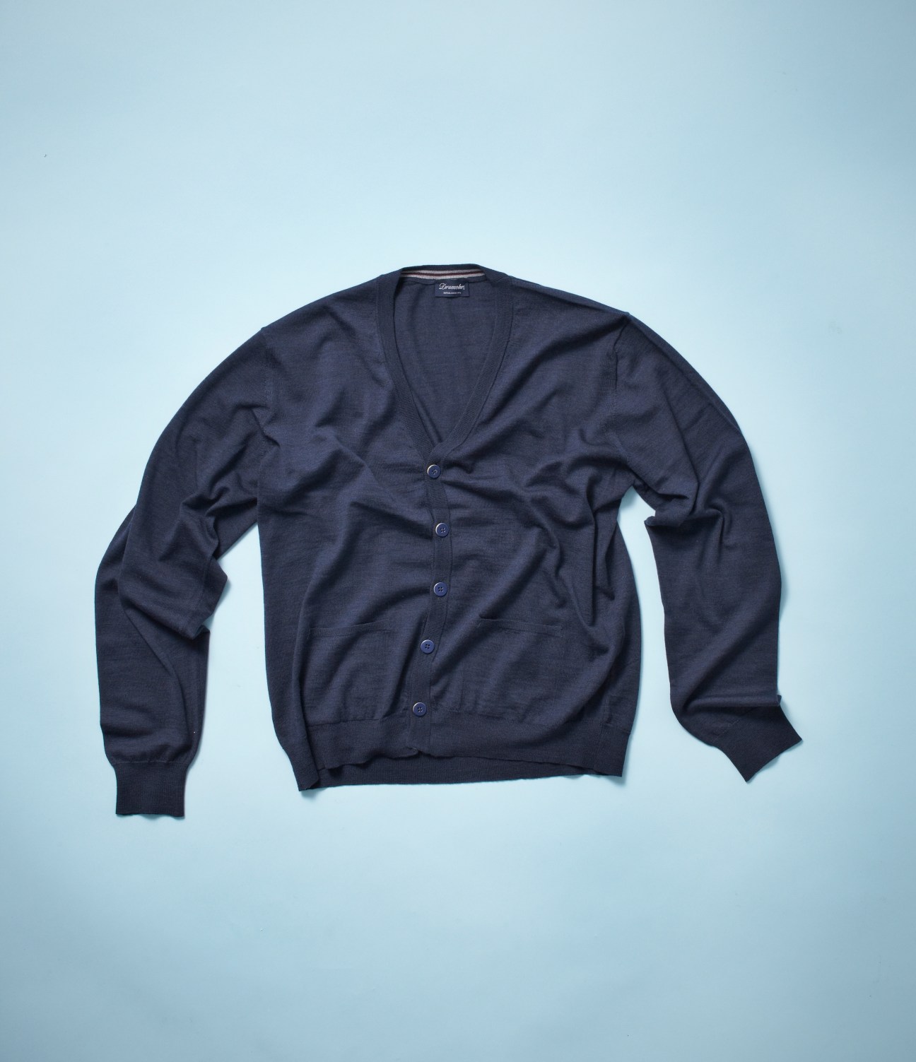 Navy blue Drumohr cardigan with button front displayed against light blue background.