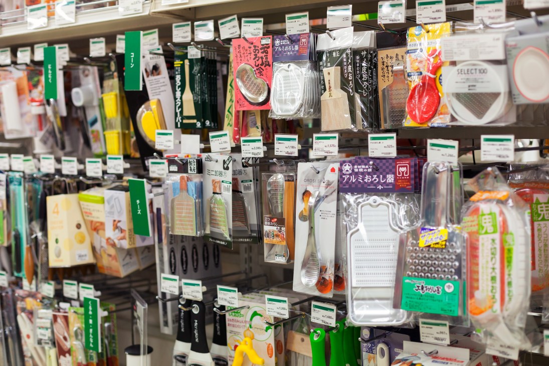 Kitchen gadgets and graters displayed on shelves with price tags at Tokyu Hands.