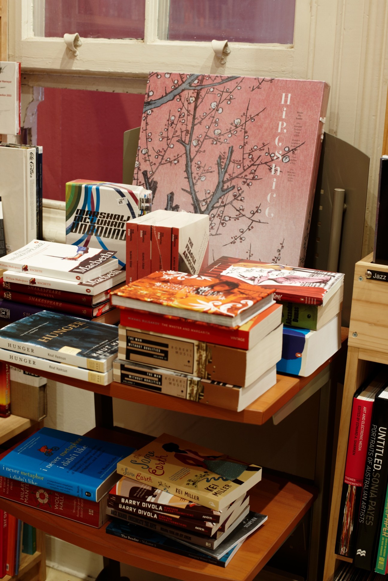 Stacked books and magazines displayed on wooden shelves in a retail store.