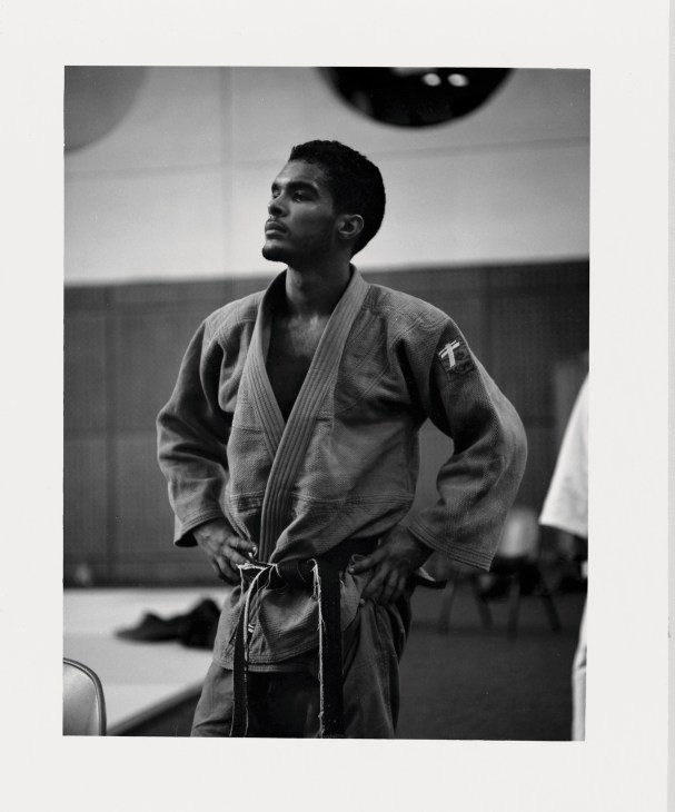 A judo competitor from Cape Verde wearing a gi and belt, standing in an indoor training facility.