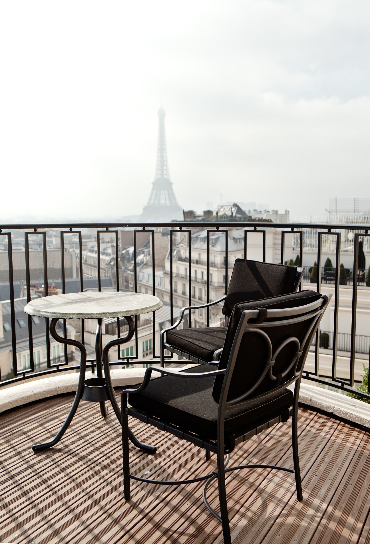 Parisian penthouse terrace with Eiffel Tower view, featuring modern seating and striped decking.