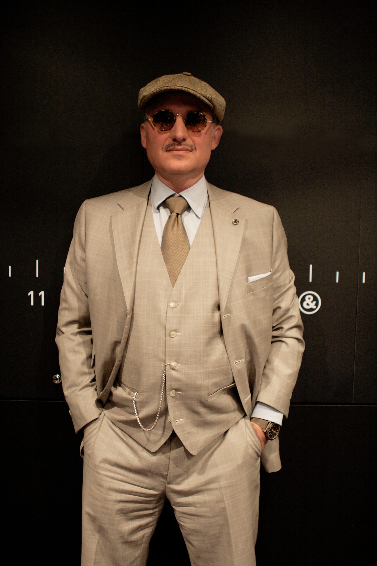Carlos A Rosillo, CEO of Bell & Ross, wearing a beige suit, cap and sunglasses against a dark background.