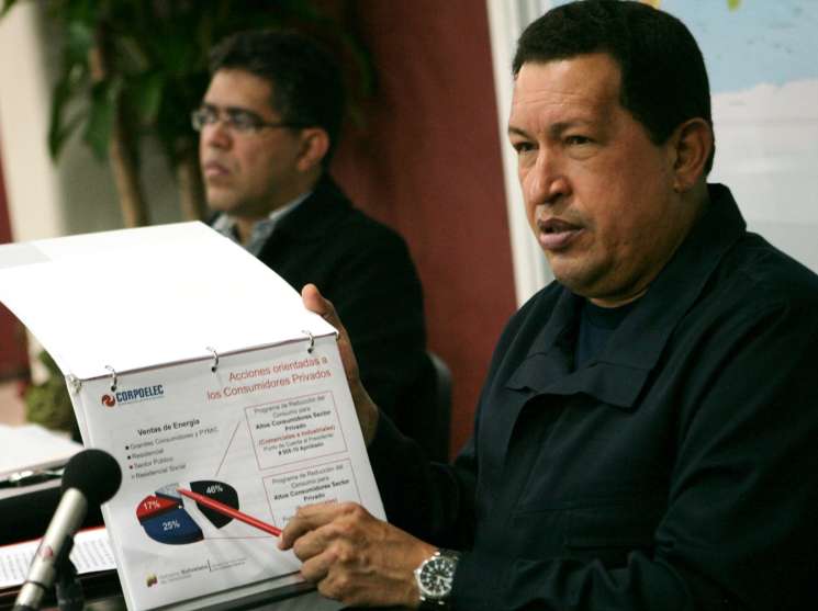A man in a dark jacket points to an energy sales chart during a presentation.