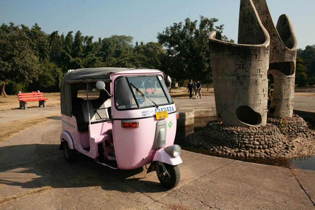 Pink GPS-equipped motorized rickshaw parked in Chandigarh with driver visible through windshield.
