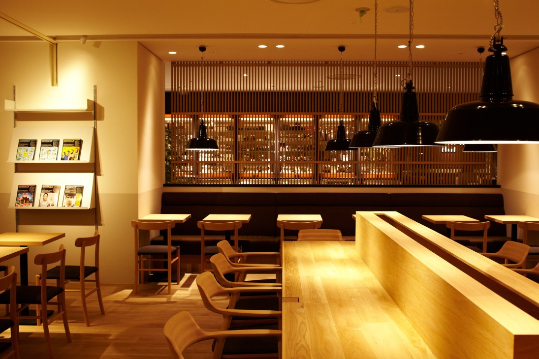 Monocle Café interior with natural wood furniture, oak floors, wooden slats, and black pendant lamps.