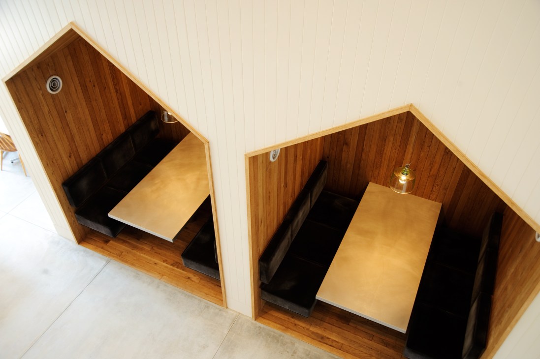 Two wooden booth seating areas with tables at The Canteen café in the Soho building.