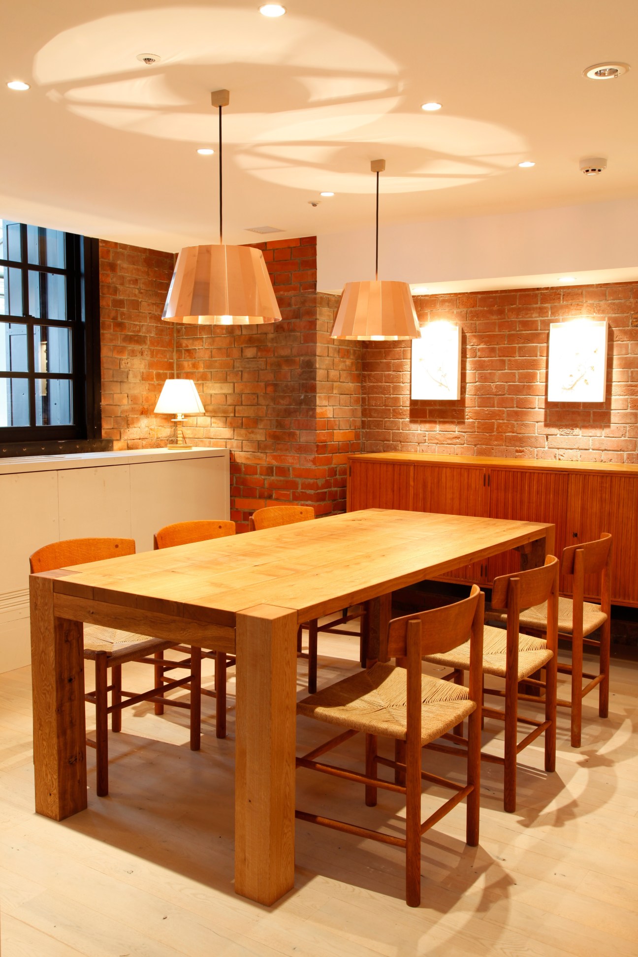 Interior of Bills restaurant in Yokohama with wooden dining table, mid-century chairs, and brick walls.