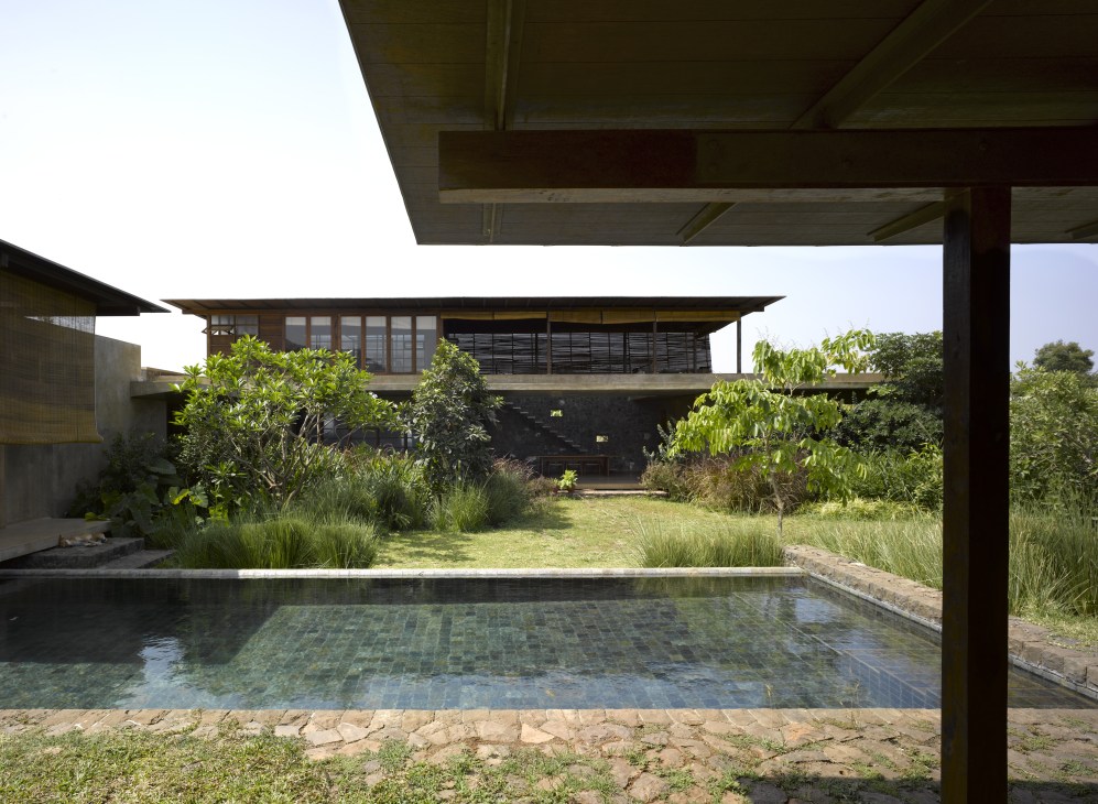 Utsav House pool surrounded by lush green vegetation and landscaping with modern architecture beyond