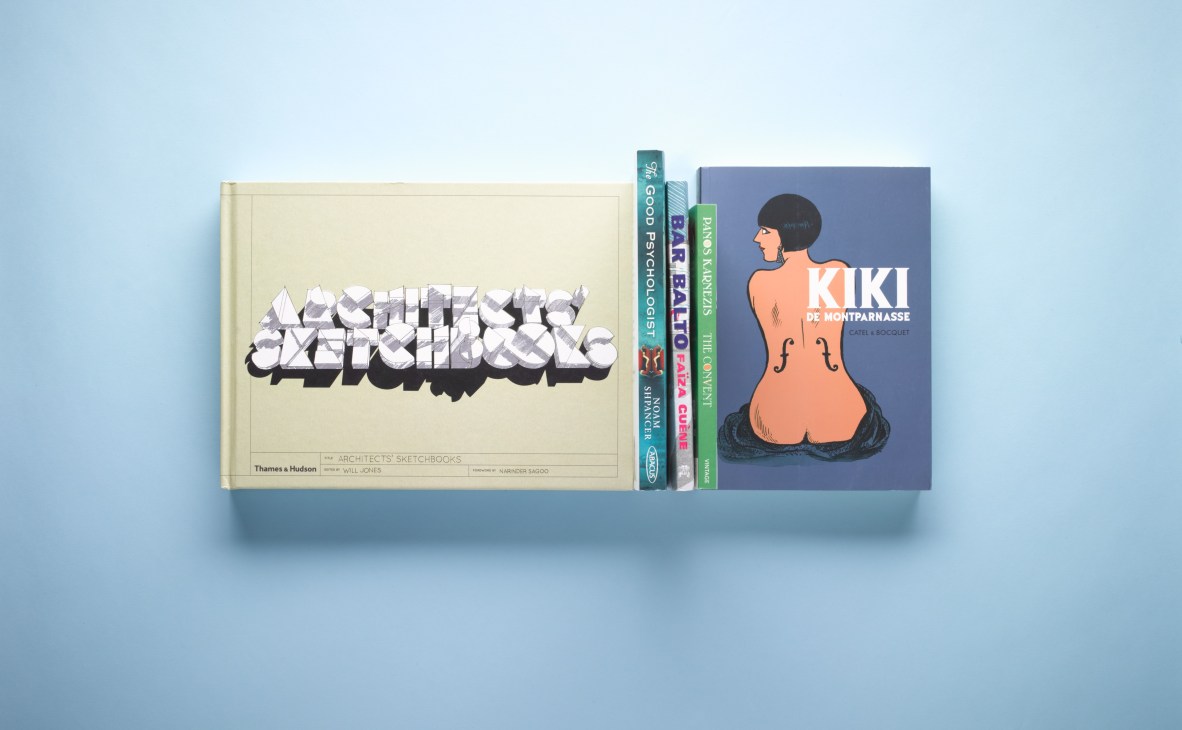 Row of books on light blue background including Architects' Sketchbooks, Kiki de Montparnasse graphic novel and other titles.
