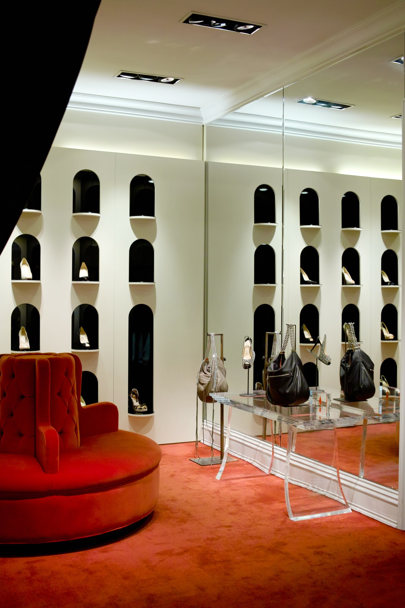 Christian Louboutin shoe section at Boon The Shop's Cheongdam women's store with red seating and wall-mounted display niches.