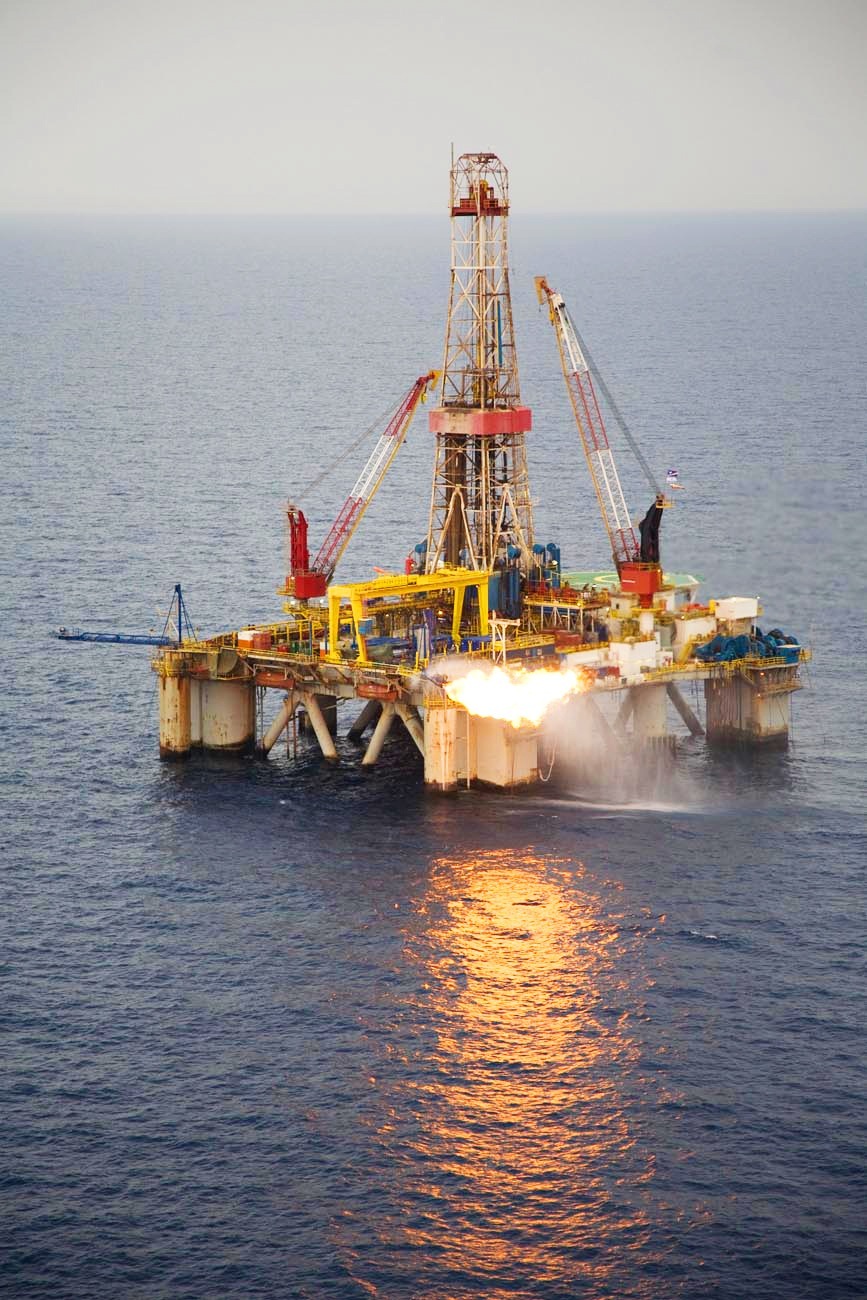 Offshore oil and gas drilling platform in the sea with tall derrick and support structures.