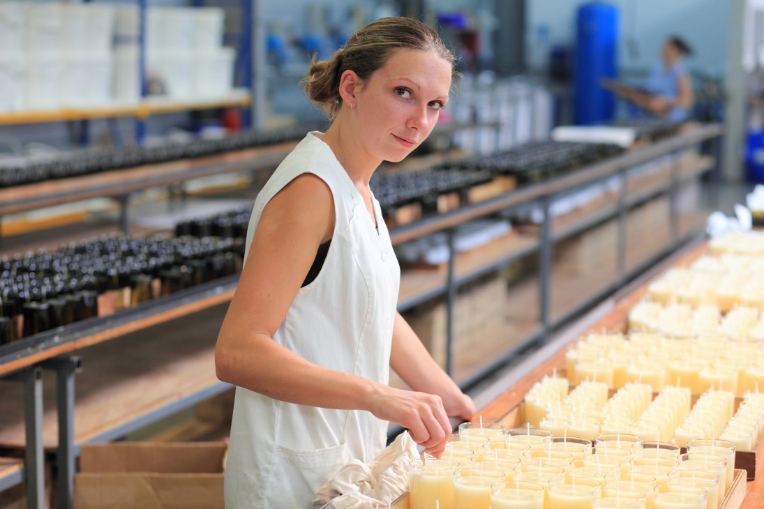 Factory worker Laëtitia Richard arranging candles on production line at Cire Trudon factory.