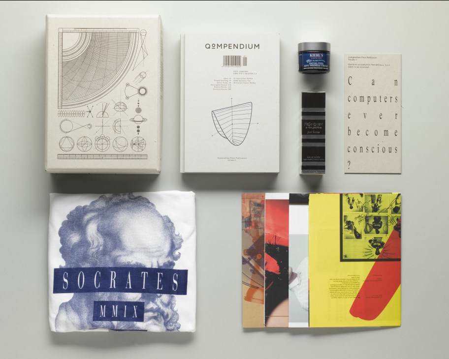 Flat lay of Qompendium magazine and various design publications and products arranged on white background.
