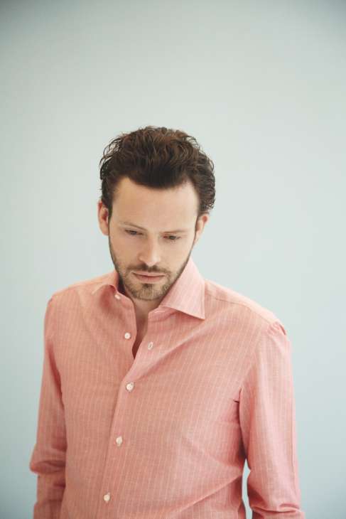 Man wearing a pink pinstriped shirt against a light blue background.