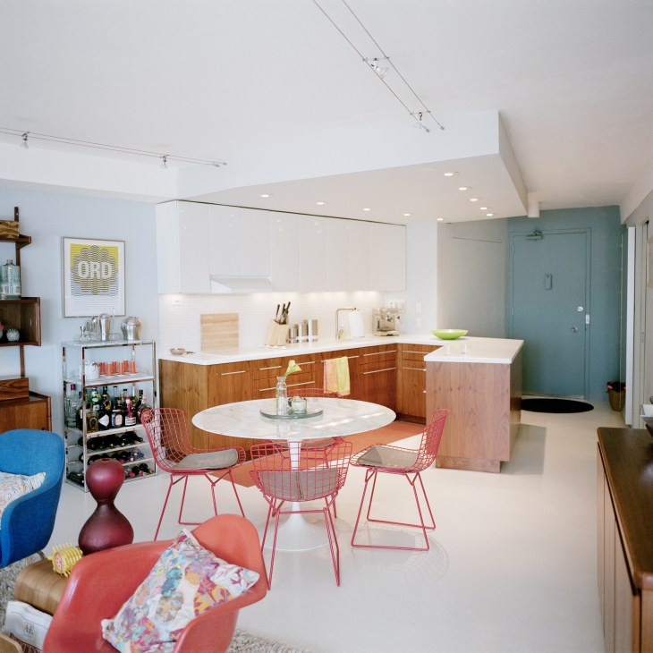 Modern open-plan kitchen and dining area with mid-century furniture and white cabinetry in a Marina City apartment.