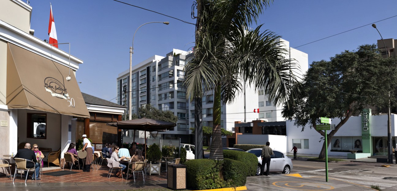 Outdoor café seating in Miraflores, Lima, with palm trees and modern buildings.