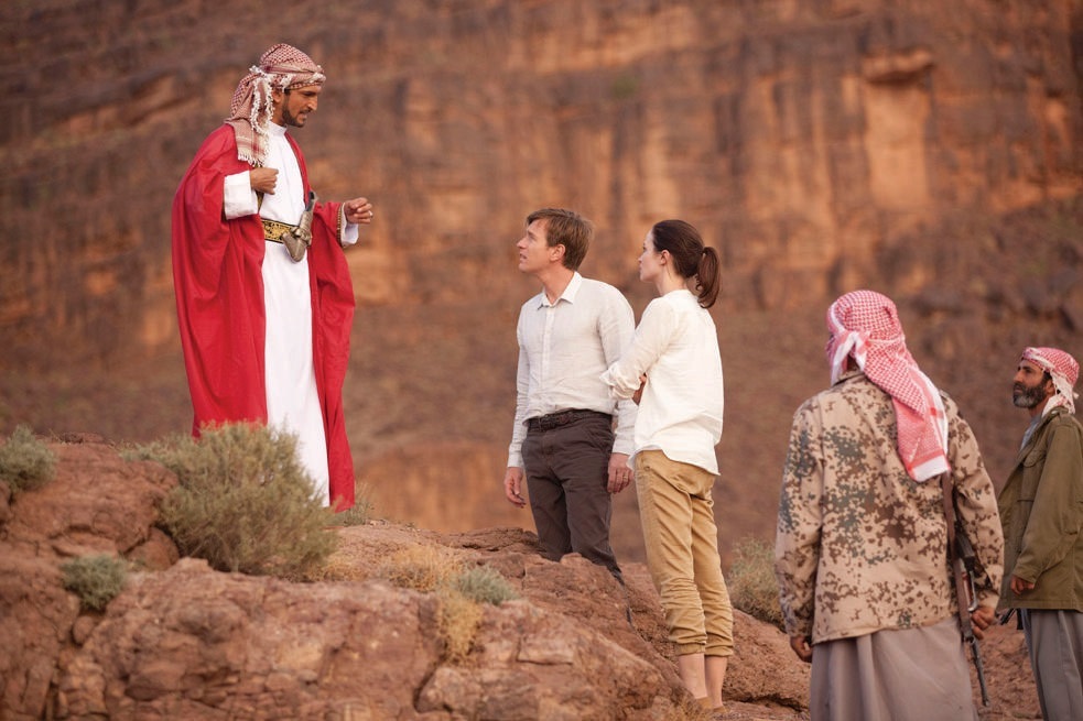 Scene from Salmon Fishing in the Yemen showing actors in desert landscape with Middle Eastern architecture.