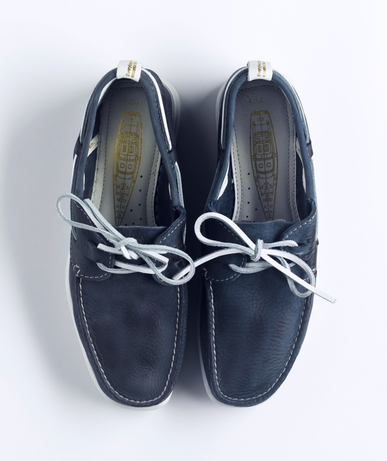 Pair of N.D.C. navy blue deck shoes with white laces and stitching, viewed from above.