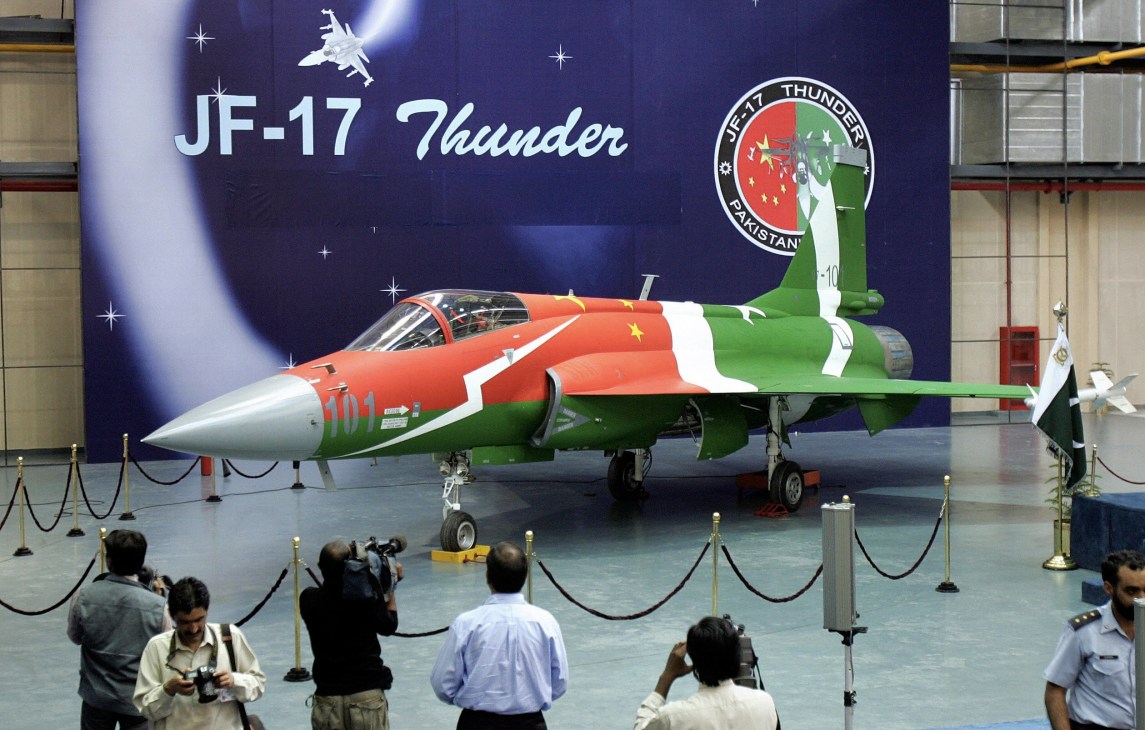 JF-17 Thunder fighter jet displayed in hangar with Pakistan and China flag insignia.