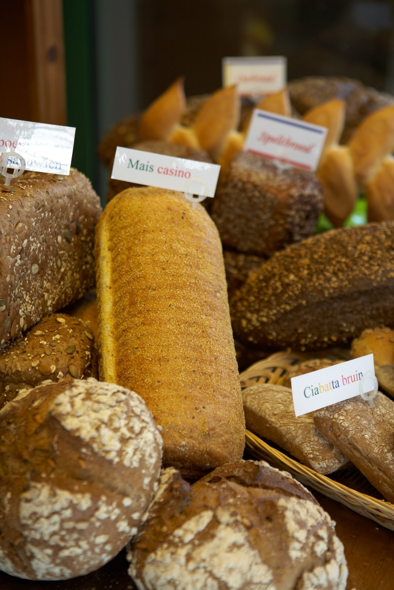 Various artisan breads with small label tags displayed at Hans & Frans bakery.