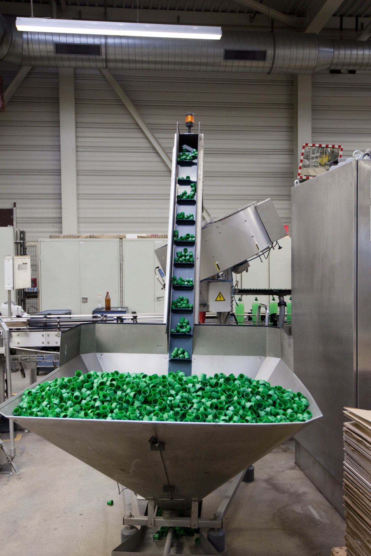 Tall vertical tower filled with green plastic Playmobil figures stacked in compartments inside an industrial warehouse.