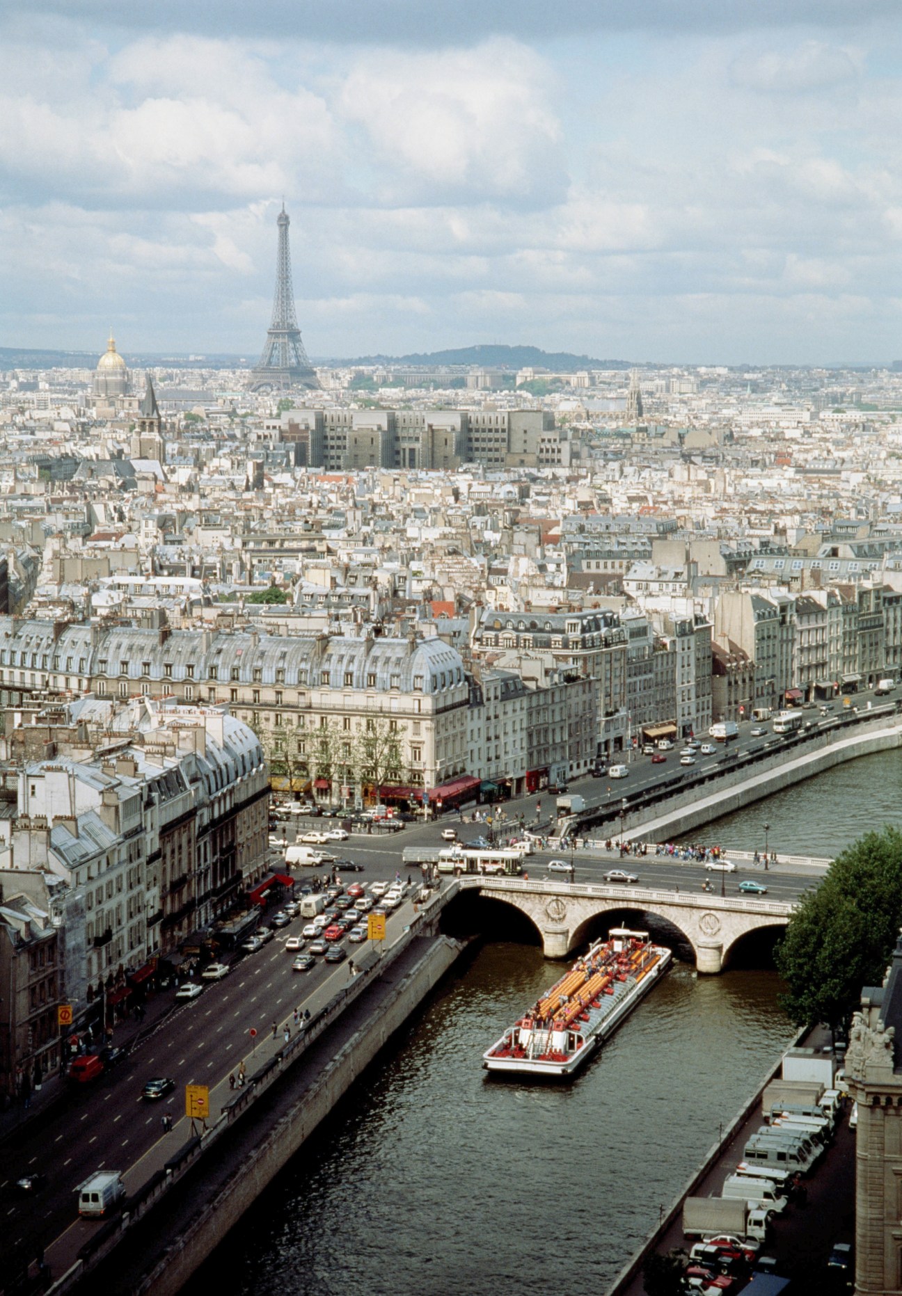 Aerial view of Paris with a barge on the Seine river, Eiffel Tower visible in the background.