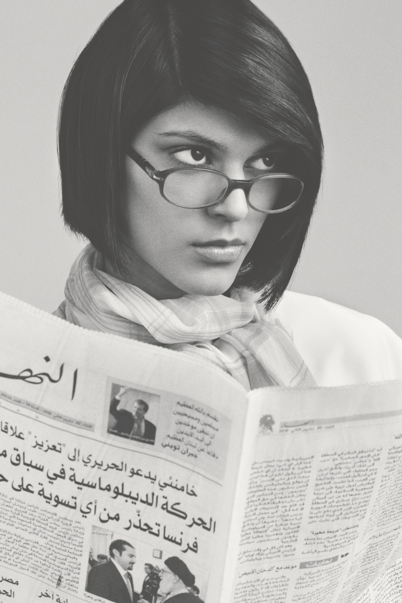 Woman wearing Persol 2921-V glasses reading a newspaper, shot in black and white.