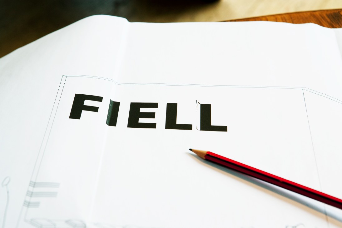 The Fiell brand identity displayed on white paper with a red pencil.