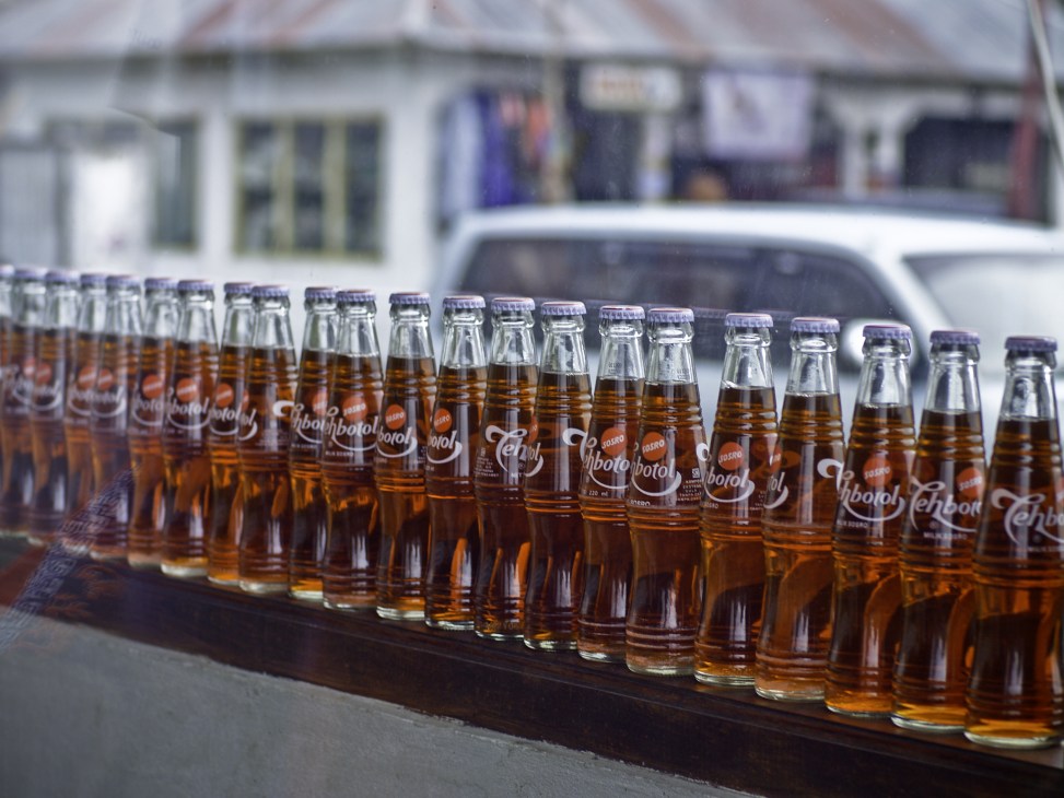 Row of Teh Botol bottled tea bottles lined up outdoors in Indonesia.