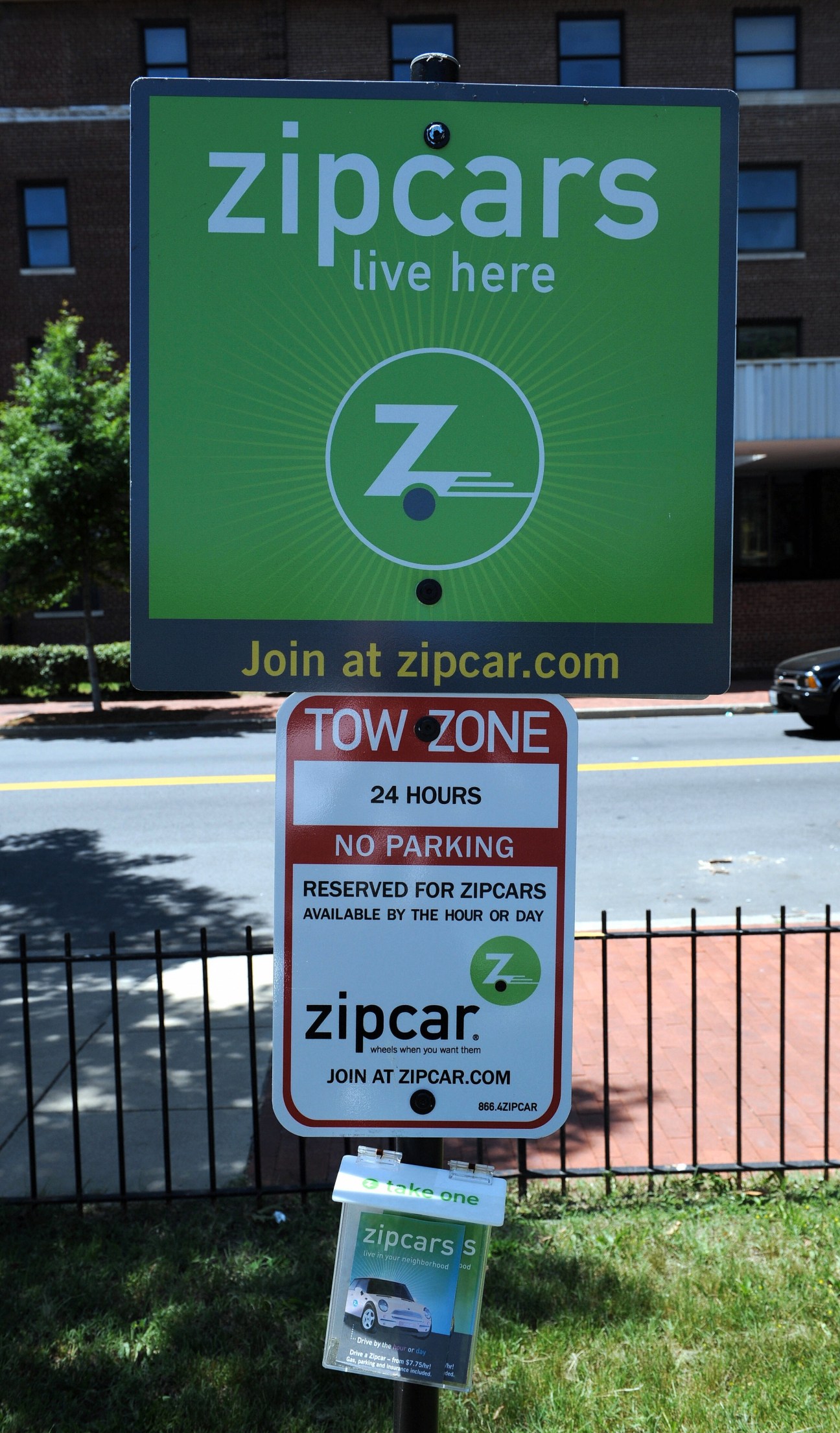 Zipcar signage displaying "live here" branding and reserved parking zone sign for car-sharing service.