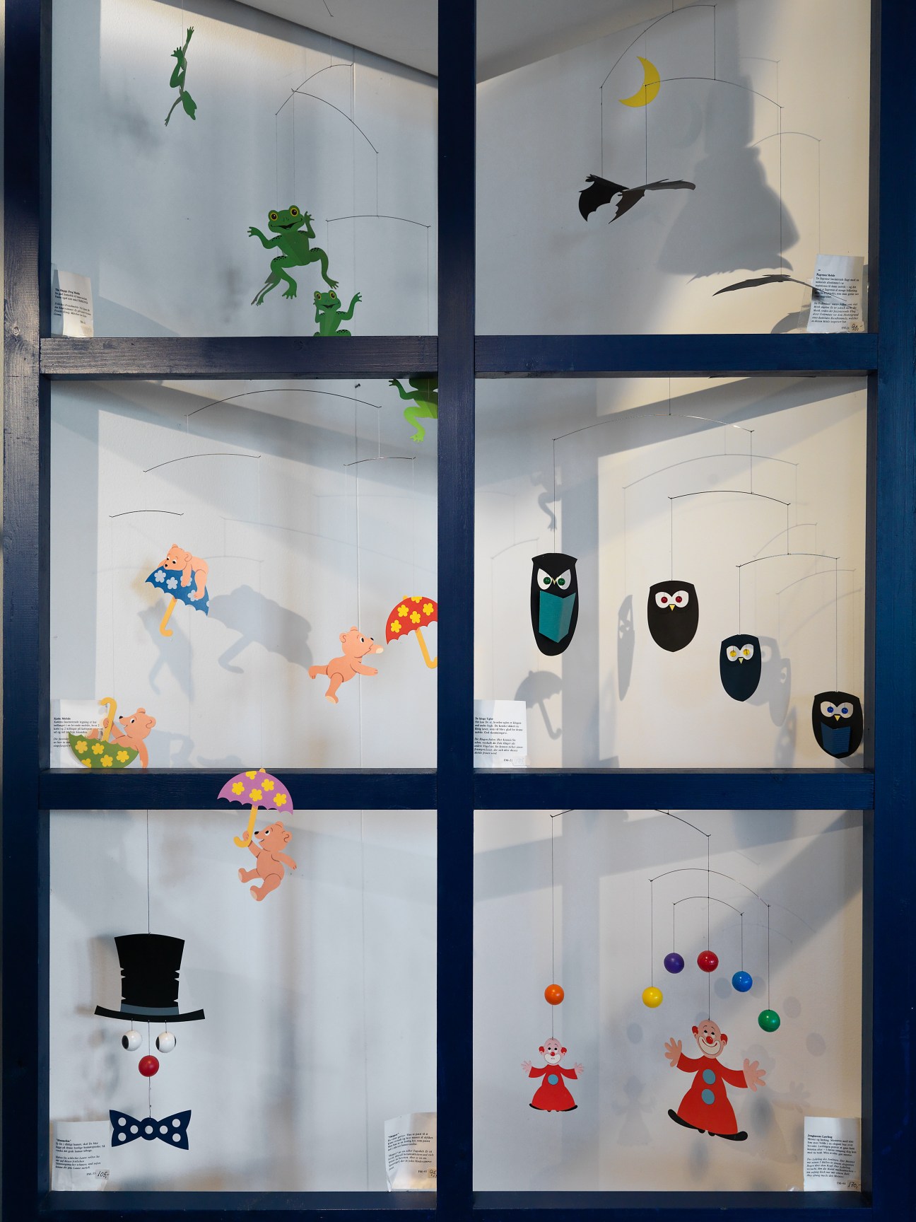 Display window featuring six Flensted hanging mobiles with colorful designs including frogs, owls, figures, and geometric shapes.