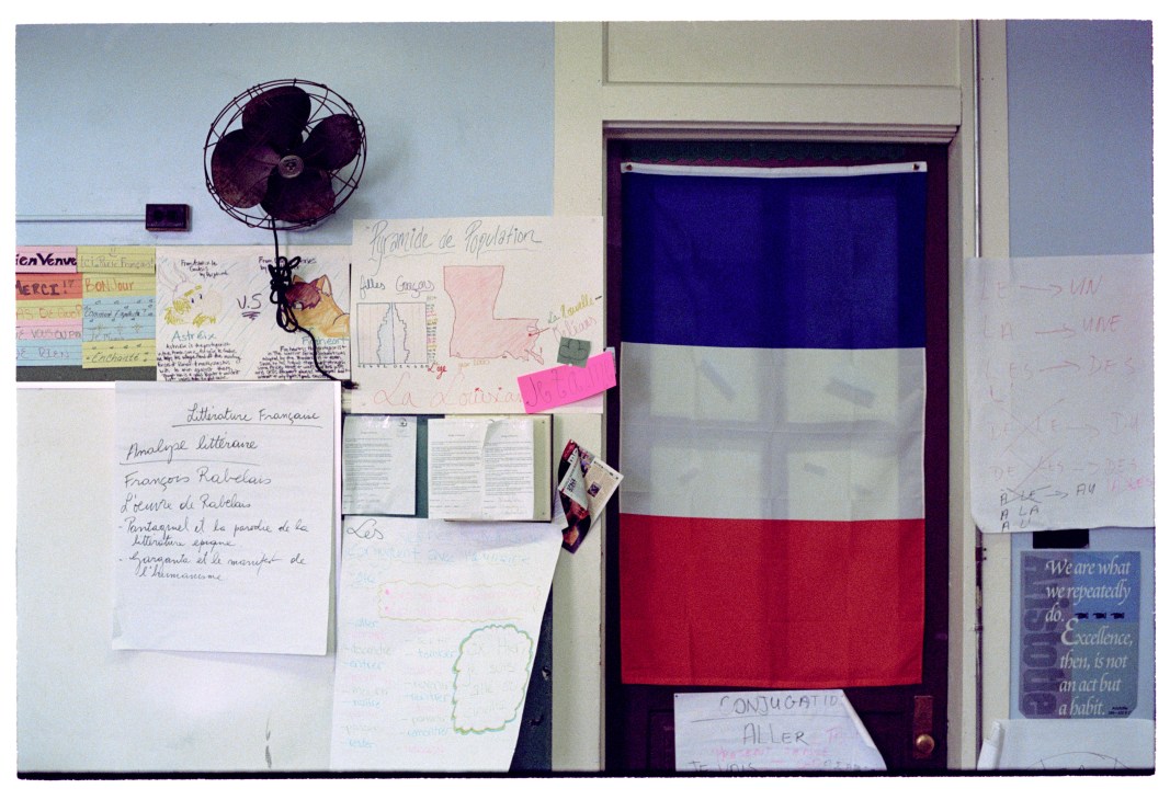 French classroom wall with student work, French flag, fan, and educational posters.