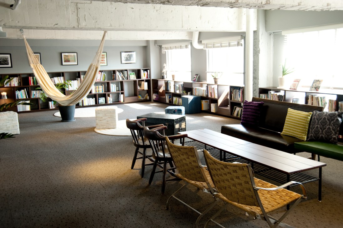 The Share's lounge and library with bookshelves, hammock, seating areas and natural light from large windows.