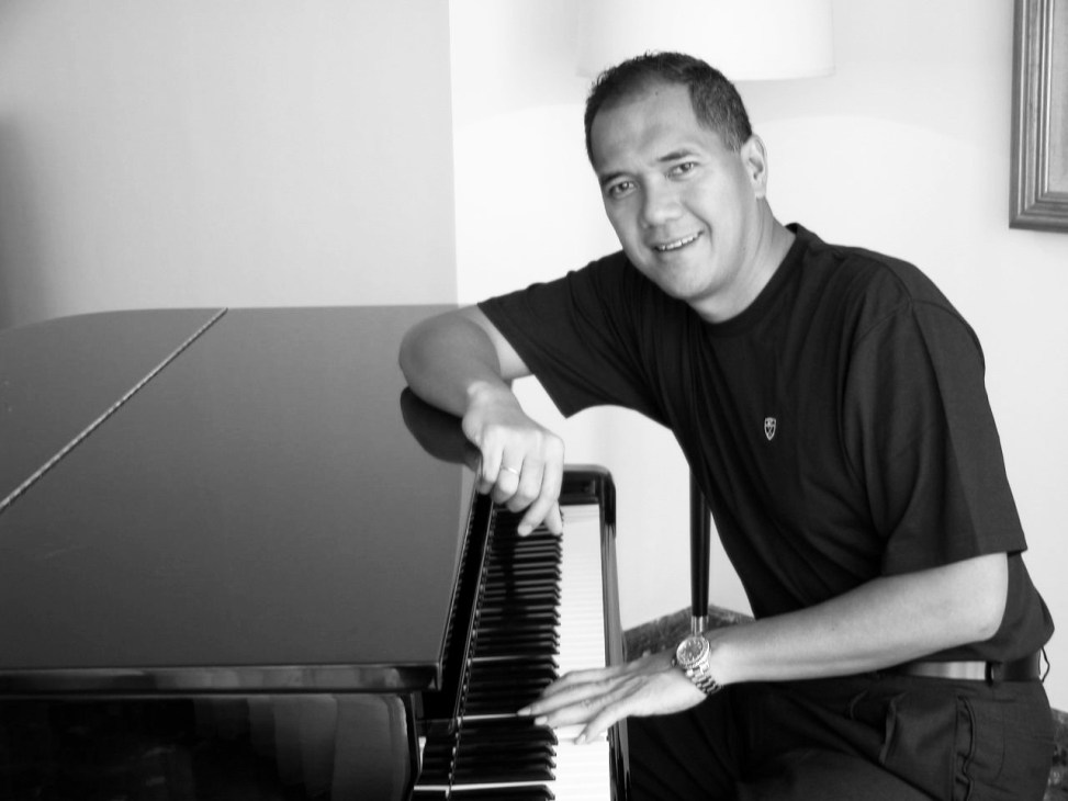 Gita Wirjawan, Indonesian banker and jazz musician, posing at a keyboard in black and white.