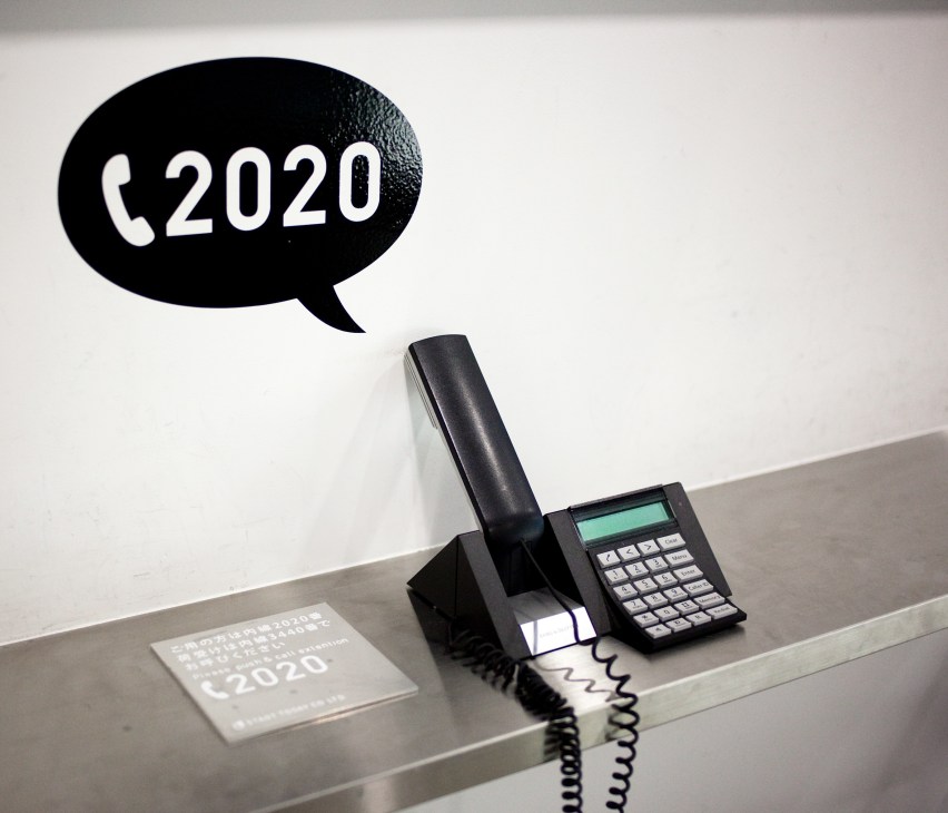 Black desk phone with coiled cord and speech bubble displaying phone number 2020 for Zozo.