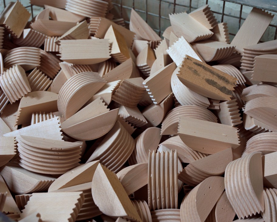 Close-up of wooden seat reinforcement pieces with ridged edges stacked together at Horgenglarus factory.