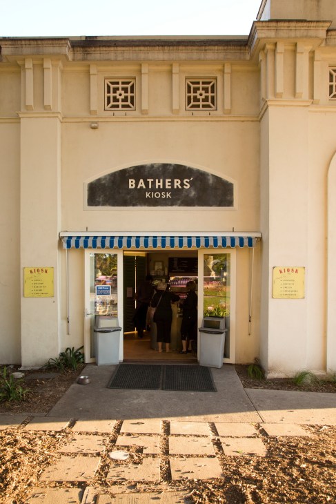 Bathers' Kiosk storefront at Bondi Beach with cream facade and blue-striped awning.