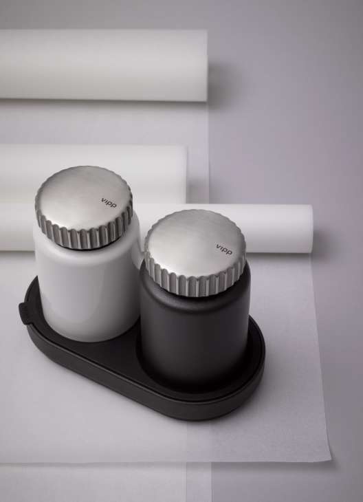 Vipp salt and pepper mills in white and black with stainless steel tops on black base tray.