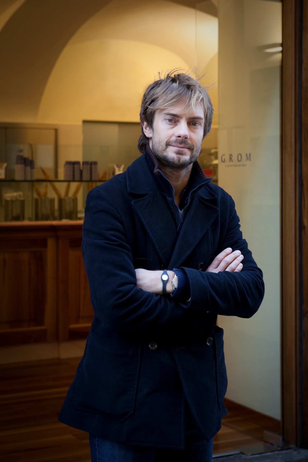 Guido Martinetti, co-founder of Grom ice cream, stands with crossed arms inside his gelato parlor in Turin.