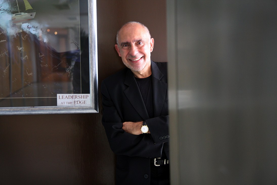 Mario García stands smiling next to a glass board with 'Leadership at the Edge' text visible.