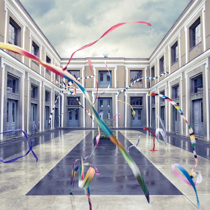 Colorful ribbons flowing through a neoclassical courtyard with symmetrical architecture.