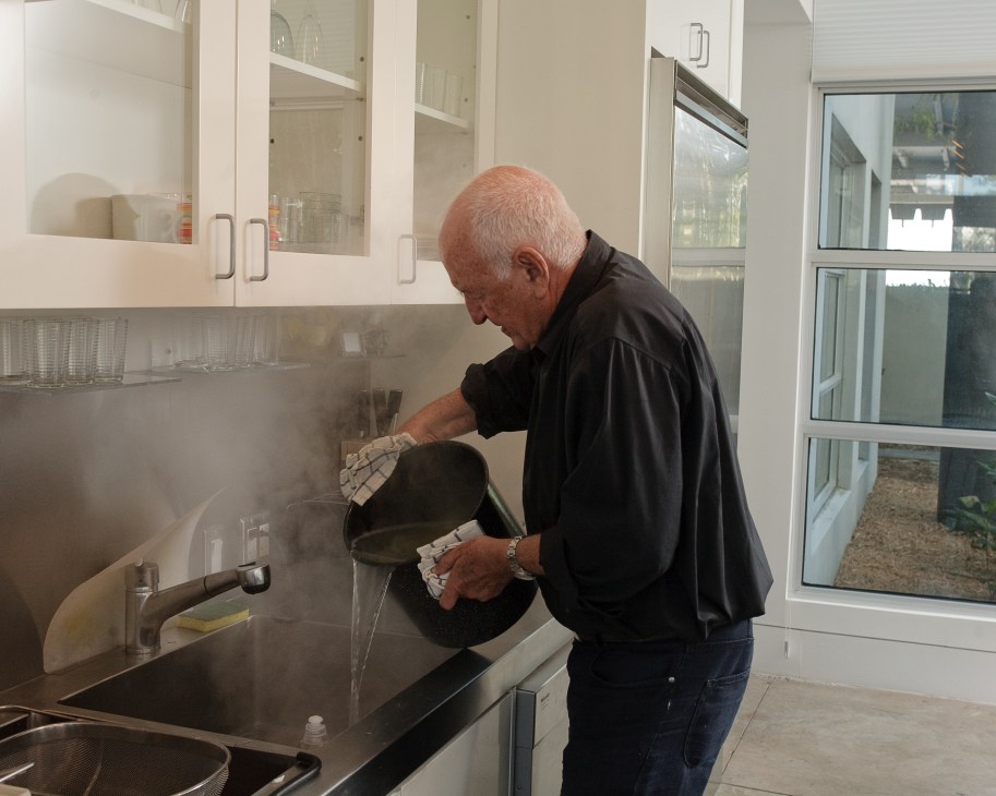 Don Rubell drains pasta at the kitchen sink in his Miami home.