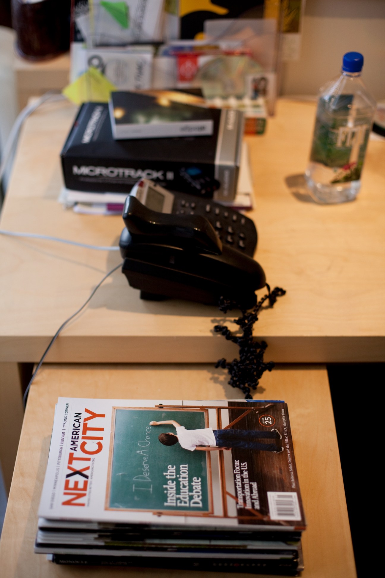 Next American City magazine on a desk with office supplies and a phone.