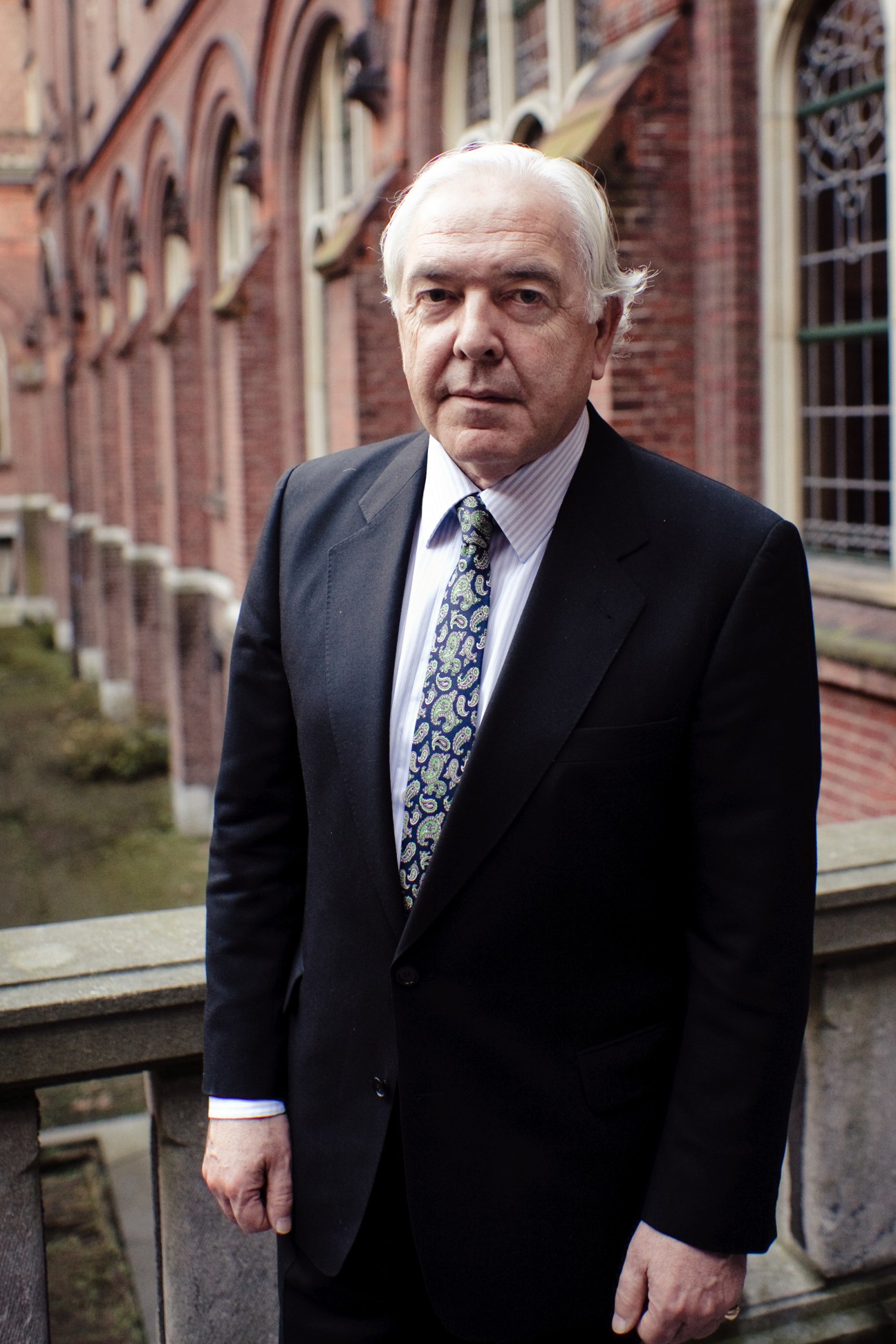 Christiaan Kröner, secretary-general of the Permanent Court of Arbitration, stands in front of the Peace Palace's brick architecture.