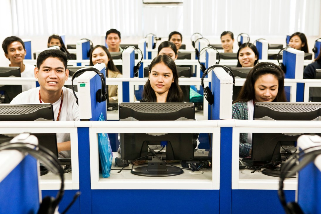Students wearing headsets sit at individual computer workstations in an English language classroom at Tesda.