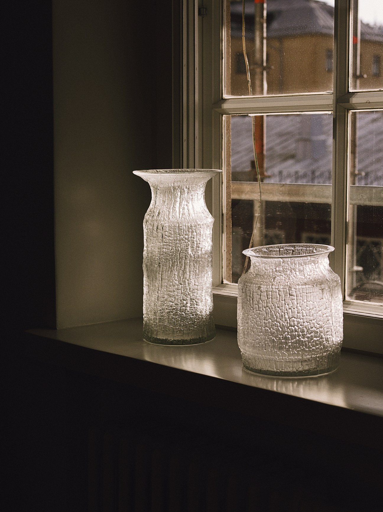 Two textured glass vases by Tapio Wirkkala for Iittala displayed on a windowsill.