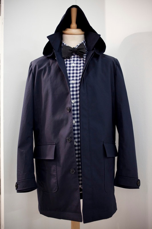 Navy wool coat on mannequin with gingham shirt and black bow tie, featuring a large collar and button front.