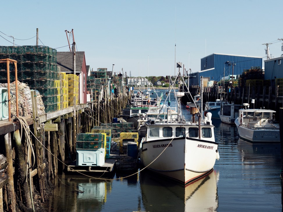 Working fishing boats and lobster traps at Portland's working waterfront with wooden piers and harbor buildings.